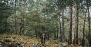 A woman in a black coat explores a lush woodland in Antalya, Türkiye.